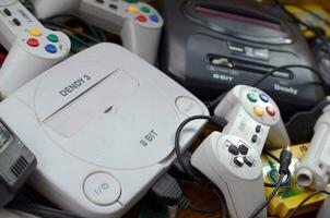 Pile of old 8-bit video game consoles and many gaming accessories like a joysticks and cartridges photo