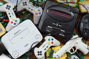 Pile of old 8-bit video game consoles and many gaming accessories like a joysticks and cartridges photo