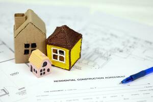 Residential construction agreement ready to sign with small toy houses and pen. Construction contract photo