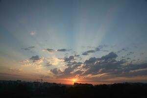 Beautiful sunrise with warm orange sunlight and beams through blue sky photo