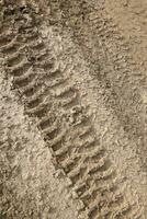 Wheel track on mud. Traces of a tractor or heavy off-road car on brown mud in wet meadow photo