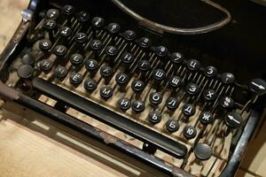 Details of an old retro typewriter in vintage style with dusty surfaces on wooden table photo