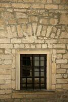 Very old window in brick stone wall of castle or fortress of 18th century. Full frame wall with window photo