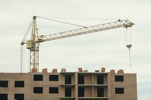 View of a large construction site with buildings under construction and multi-storey residential homes. Tower cranes in action on blue sky background. Housing renovation concept photo