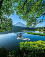 Tranquil Scene of a Green Forest Lake with Reflection of Trees,Tranquil forest lake with mountains, greenery, and leisurely boating photo