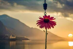 a flower is hanging from a chain over a lake. AI-Generated photo