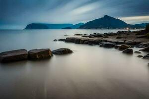 a long exposure photograph of rocks on the shore of a body of water. AI-Generated photo