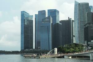 Singapore, August 19, 2023-Group of people walking on the walkway to Merlion with crowded of high modern buildings in background photo