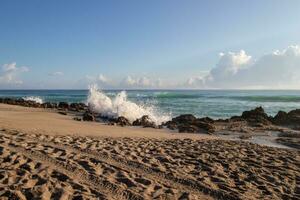 Sandy beach and crashing waves on rocks photo