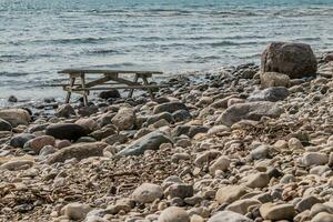picnic mesa en un rocoso línea costera foto