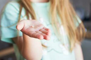 Little girl's hand holding and showing her fallen milk front tooth close up. photo