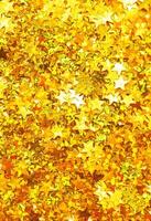Glittering background of golden sequins in form of stars closeup. Sparkle festive texture. photo