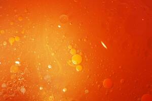 oro petróleo burbujas cerca arriba. círculos de naranja agua macro. resumen brillante amarillo antecedentes foto