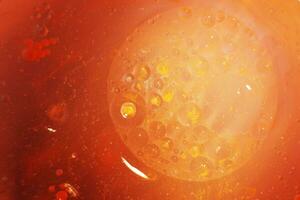 oro petróleo burbujas cerca arriba. círculos de naranja y rosado agua macro. resumen brillante amarillo antecedentes foto