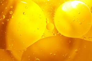 oro petróleo burbujas cerca arriba. círculos de naranja agua macro. resumen brillante amarillo antecedentes foto