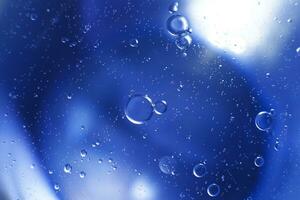 las burbujas de aceite se cierran. círculos de agua macro. fondo azul claro abstracto foto