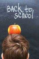 an apple on a child's head near chalkboard. Back to school concept background photo