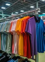 fila de de moda polo camisetas para hombre en de madera percha o estante en un ropa boutique Al por menor tienda concepto por ai generado foto