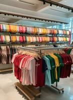 Row of fashionable polo t-shirts for man on wooden hanger or rack in a clothing boutique retail shop concept by AI Generated photo