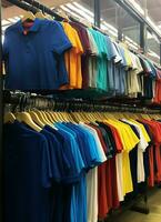 Row of fashionable polo t-shirts for man on wooden hanger or rack in a clothing boutique retail shop concept by AI Generated photo