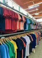 Row of fashionable polo t-shirts for man on wooden hanger or rack in a clothing boutique retail shop concept by AI Generated photo