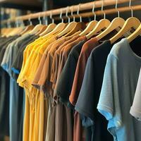 Row of fashionable polo t-shirts for man on wooden hanger or rack in a clothing boutique retail shop concept by AI Generated photo