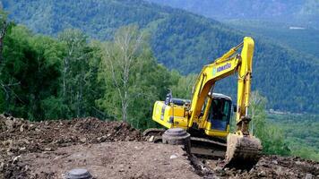 un amarillo excavador trabajos en el montañas. construcción de carreteras video