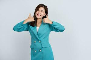Young Asian business woman in bright green suit showing thumbs up isolated on green background photo