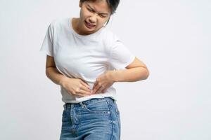 Asian woman was sick with stomach ache and she putting her hands on her belly on white background. photo