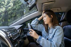 asiático mujer con dolor de cabeza en un coche foto