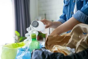 Woman wearing casual clothes is sorting recyclables with different trash cans and colorful garbage bags at home. photo