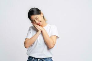 Tired Asian woman wearing a white t-shirt is napping alone on a white background. photo