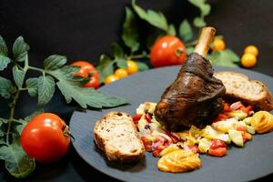 Grilled lamb shank from the charcoal grill with a fresh salad photo