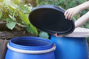 Closeup hand hold lid to cover water jar to protect from mosquito to breed inside or other  insects or dust go into water. Concept, campaign to stop mosquitoes cycle to lay eggs in water container photo