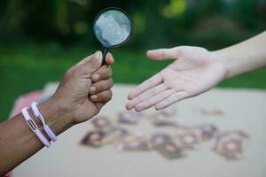 la mano de primer plano sostiene una lupa para inspeccionar las líneas de la palma. concepto, quiromancia, astrología. adivinación, misterio, magia, fortuna, destino. predicción para la vida futura, eventos. predicción palmista. foto