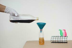 Close up hand holds bottle of soft drinks water to pour into the funnel bottle for doing science experiment.Concept, Science process about reaction of chemical substance. photo