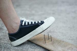 de cerca hombre vestir Zapatos es pisar en oxidado metal uña en madera. concepto, inseguro , riesgo para peligroso tétanos. ser Cuidado y Mira alrededor durante caminando en el piso o riesgo lugares. accidente foto