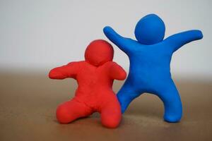 Red and blue plasticine people. Human figures from plasticine sculpture. Concept, friendships, partnerships and relationships between people. Sculting enhance imagination. photo