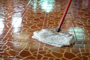 Close up man use a mop by using old towel to mop the floor. Concept, household chore in daily life. Hygienic and sanitary. Mop the dust, wipe the floor. Cleaning house. Maintaining tile floors. photo