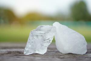 blanco alumbre piedras en de madera piso antecedentes. tailandés utilizar eso a obtener eliminar de cuerpo olor y columpio el sucio agua a hacer agua claro. útil para belleza y spa tratamiento. utilizar a tratar agrietado tacones foto