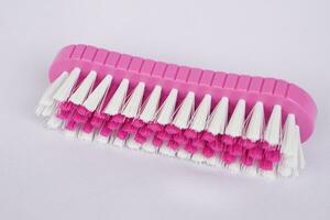 Pink brush made of plastic and nylon for washing cloth or cleaning floor on white background. Concept, equipment for washing, scrubbing and cleaning dirty cloth, carpet or surface. Daily chores tool. photo