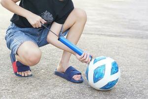 de cerca chico es bombeo aire dentro fútbol. concepto, portátil deporte equipo para inflar pelota. fácil y conveniente ese niños lata hacer sí mismos con un manual bomba. foto