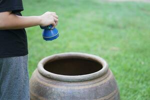 Close up boy hold flashlight to explore mosquito larvae or insects that breed inside water jar. Concept, campaign to stop mosquitoes cycle to lay eggs in water container. Check, explore and get rid of photo