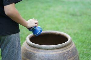 Close up boy hold flashlight to explore mosquito larvae or insects that breed inside water jar. Concept, campaign to stop mosquitoes cycle to lay eggs in water container. Check, explore and get rid of photo