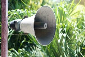 Vintage bullhorn, megaphone, speakers was installed on pole with green trees background . Concept , Equipment for public announcement or warning for danger or emergency events. photo