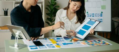 UX developer and ui designer brainstorming about mobile app interface wireframe design with customer breif and color code at office. photo