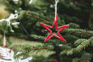 rojo hecho a mano estrella en un Navidad árbol exterior. bricolaje creativo ideas para niños. ambiente, reciclar, reciclado y cero residuos concepto. selectivo atención foto