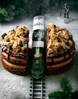 Playful conceptual image of toy train driving through the chocolate cake. It's snowing sugar powder and there is a miniature alpinist walking towards the cake mountain photo