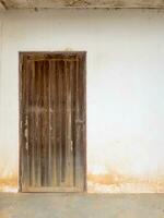 The old wooden door with the brass knob on the white wall. photo