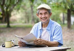 portrait smiling senior man holding paper map,looking at a camera while travelling in the national park photo